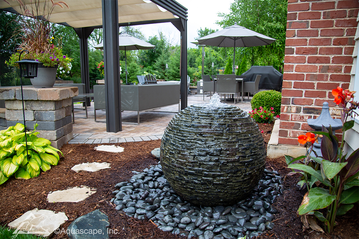 Aquascape stacked slate sphere fountain in landscaped patio